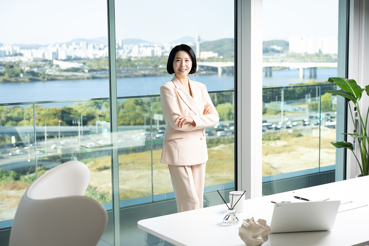 통창 앞에서 팔짱을 끼고 선 여성 비즈니스 화보